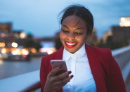 Young woman looking at cell phone outside at night